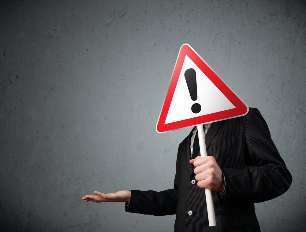 Businessman holding a red traffic triangle warning sign in front of his head-1